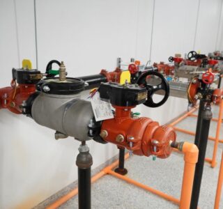 Why are backflow preventers required in fire sprinkler systems?